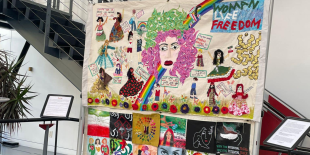 Colorful quilt with a central image of a person with long, curly lavender hair. 